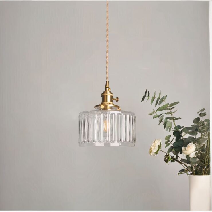 Lustre simple en verre des années 30 suspendu dans un salon moderne avec un bouquet de fleurs blanches en arrière-plan, lumière douce diffusée à travers l’abat-jour en verre strié.