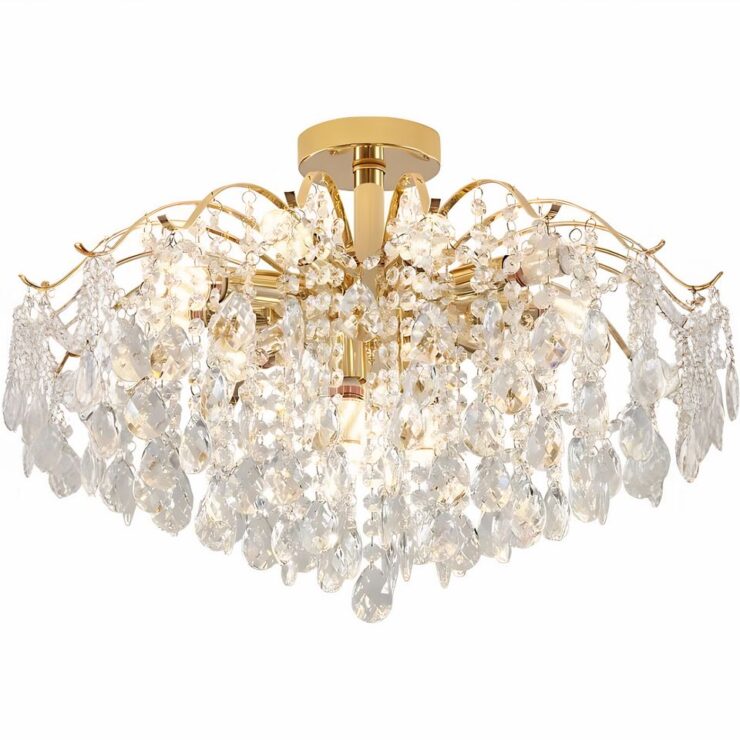 Lustre à pampilles effet gouttes de cristal. Sa structure est dorée en forme de branches de saule pleureur. A chaque extrémité, une goutte transparente. Sur fond blanc.