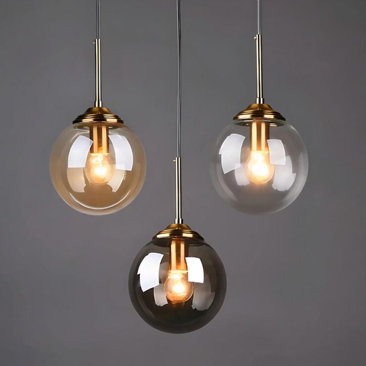 Présentation des trois couleurs de fumage du globe du lustre de bureau en forme de grosse ampoule disponible en noir, en blanc et en rose poudré doré. Le tout sur un mur unis gris foncé.