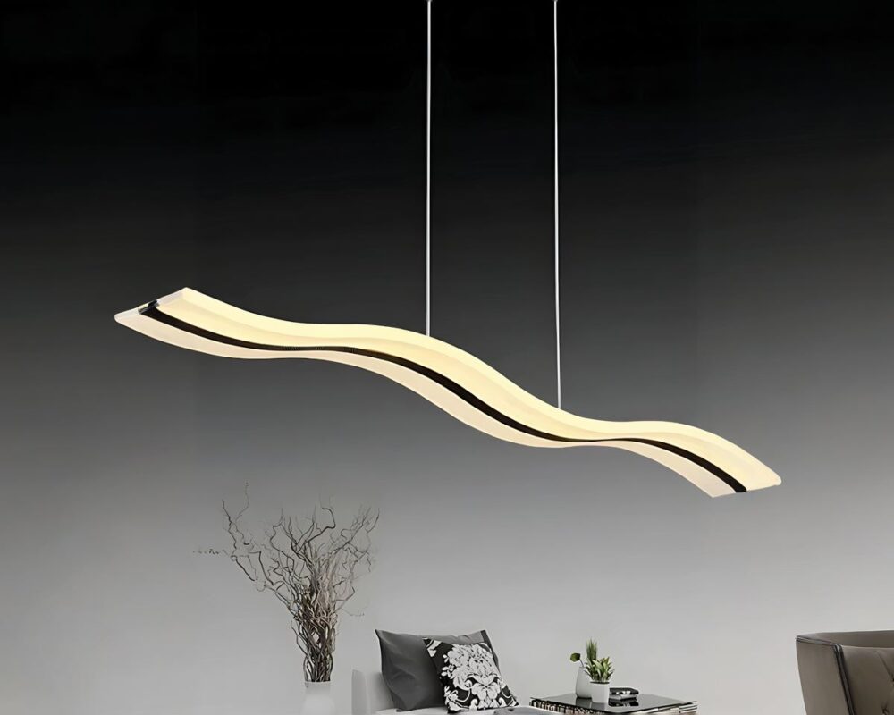 Lustre LED suspendu en forme de vague avec une ligne noire au centre. Il est suspendu par deux câbles fins. Dans une pièce sombre, la partie haute est noire, la partie basse grise avec de la décoration simple sur le bas de la photo.