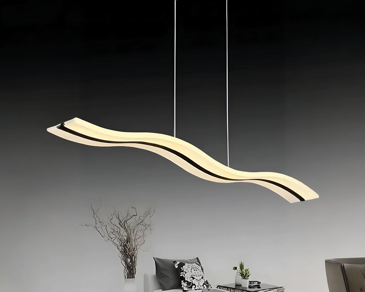 Lustre LED suspendu en forme de vague avec une ligne noire au centre. Il est suspendu par deux câbles fins. Dans une pièce sombre, la partie haute est noire, la partie basse grise avec de la décoration simple sur le bas de la photo.