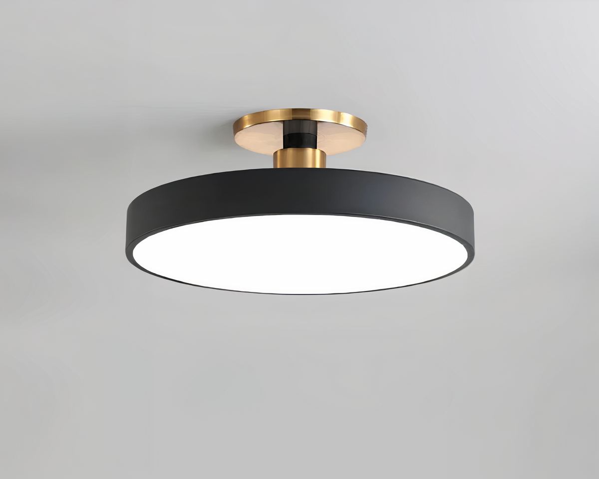 Un lustre sans fil au design nordique coloré en noir. Le socle rond fixé au plafond est doré. En-dessous, un cercle noir, le dessous en acrylique diffuse la lumière. Sur fond gris.