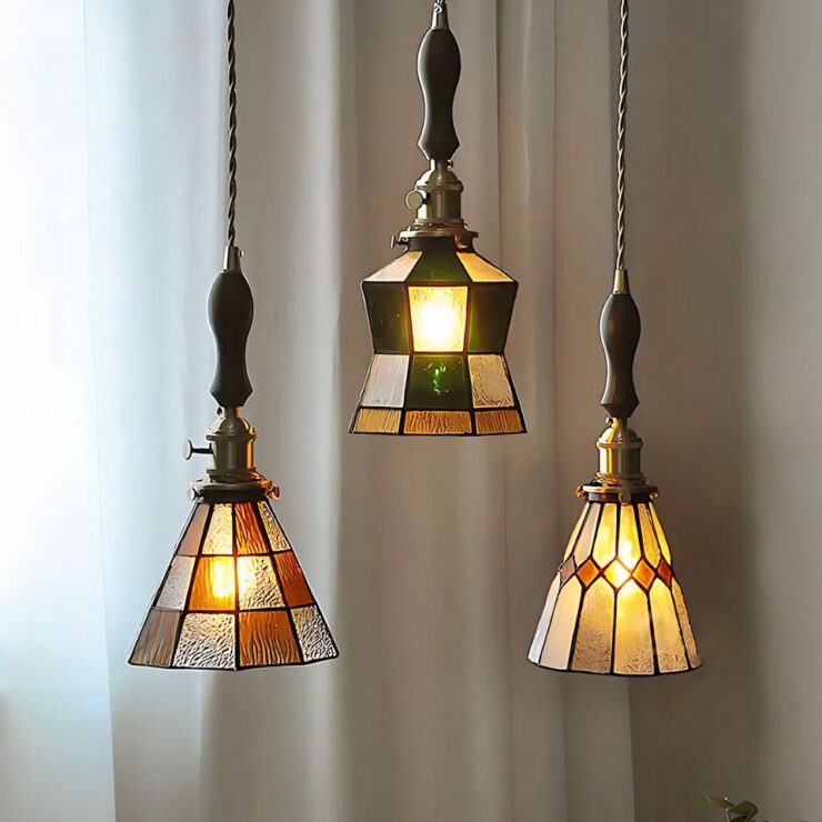 3 lustres suspendus en verre peint années 30, détails de motifs géométriques colorés avec une lumière douce filtrant à travers des vitraux.