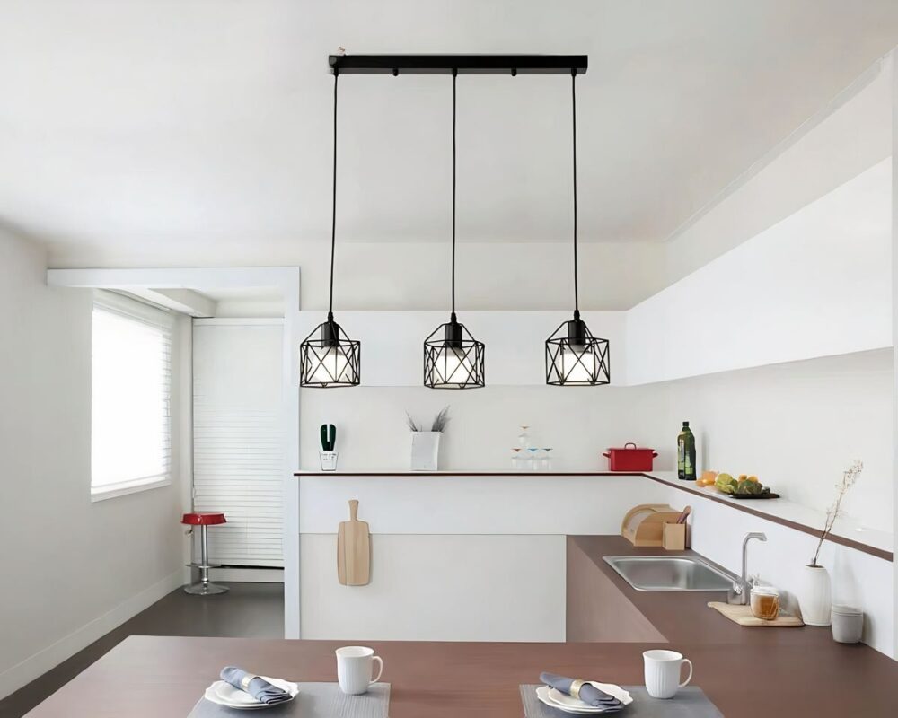 Lustre barre à trois suspensions style industriel suspendu au-dessus d'un îlot central dans une cuisine.