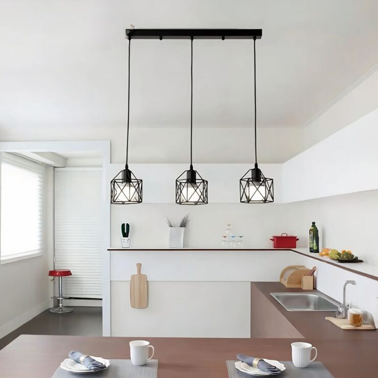 Lustre barre à trois suspensions style industriel suspendu au-dessus d'un îlot central dans une cuisine.