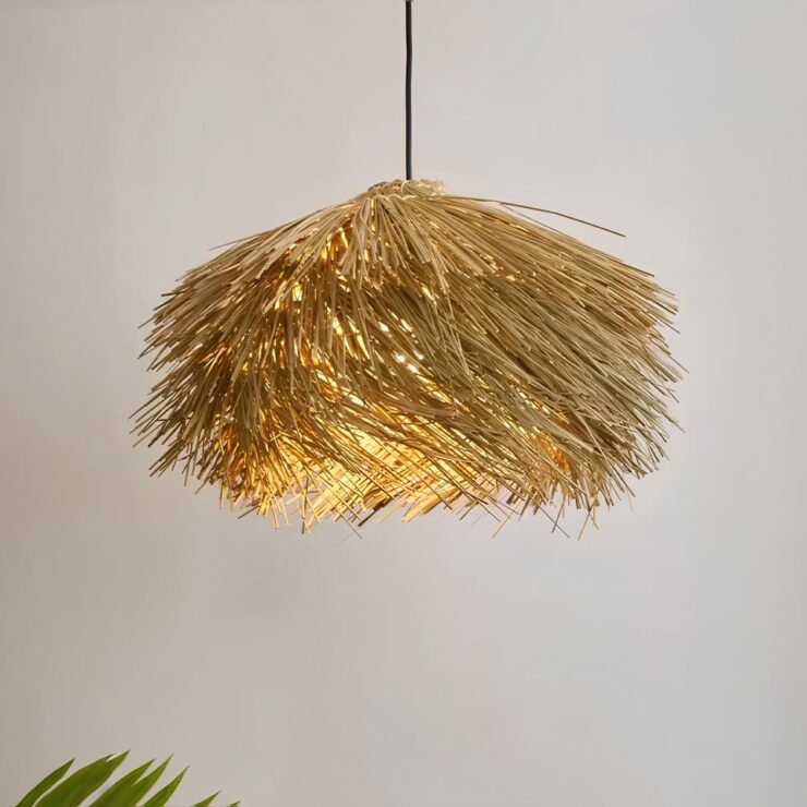 On voit un lustre bali en rotin style boho de couleur beige suspendu. Le mur derrière est beige. on aperçoit une plante verte dans l'angle à gauche.