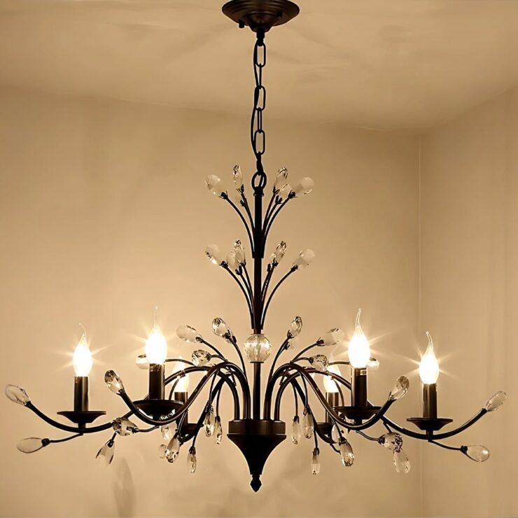 Lustre hollandais noir élégant fixé sur un plafond blanc. Il est composé de 6 branches fines noires au bout desquelles se trouvent une ampoule style chandelier allumée. Des branches noires et des détails en cristal transparent se trouvent sur l'ensemble du lustre. La lumière diffusée est blanc chaud.