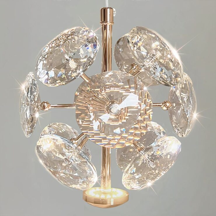 Petit lustre d'entrée avec facettes en cristal sur une structure dorée. Sur fond gris.