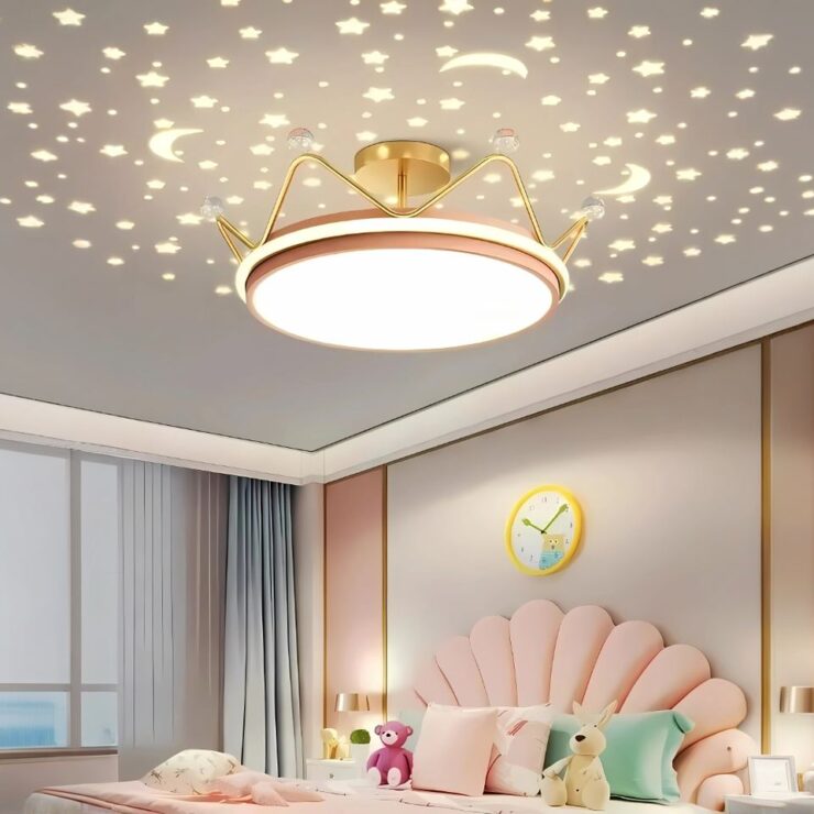 Un lustre chambre fille couronne enchantée projette des motifs d'étoiles et de lunes lumineuses sur le plafond, créant une atmosphère magique dans une chambre d'enfant décorée avec des tons roses et des pastels.