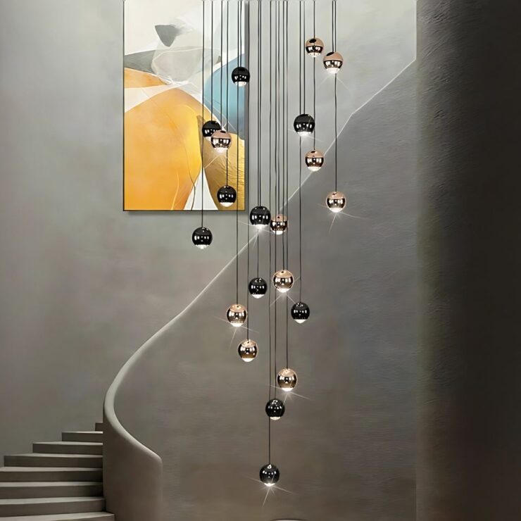 Lustre en cascade pour escalier, composé de sphères dorées et noires suspendues à différentes hauteurs, créant un effet visuel élégant et moderne.