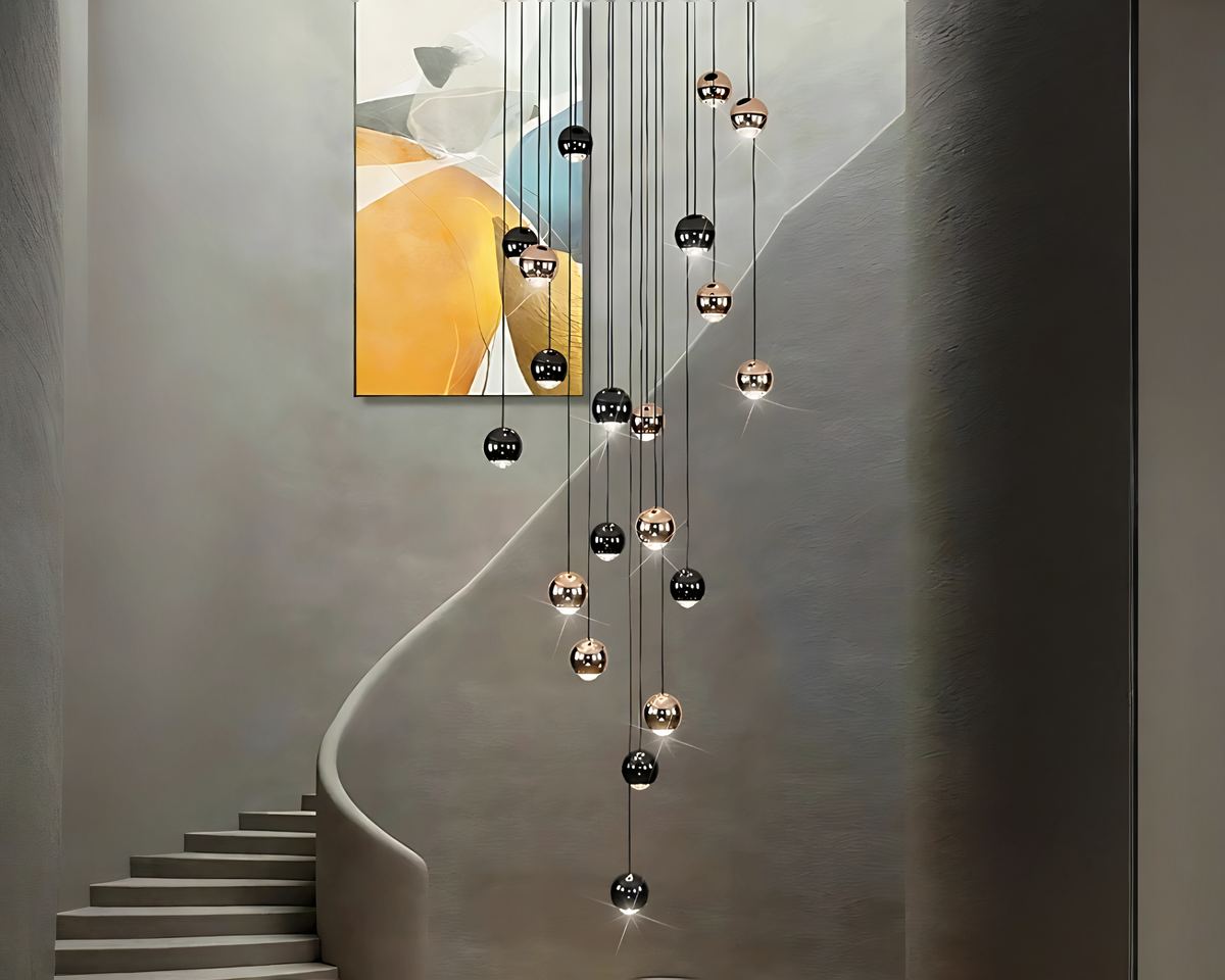 Lustre en cascade pour escalier, composé de sphères dorées et noires suspendues à différentes hauteurs, créant un effet visuel élégant et moderne.