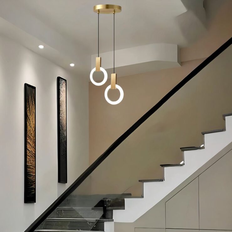 Lustre pour escalier composé de deux cercles lumineux suspendus, avec une fixation dorée, apportant une touche moderne et élégante à l'espace.