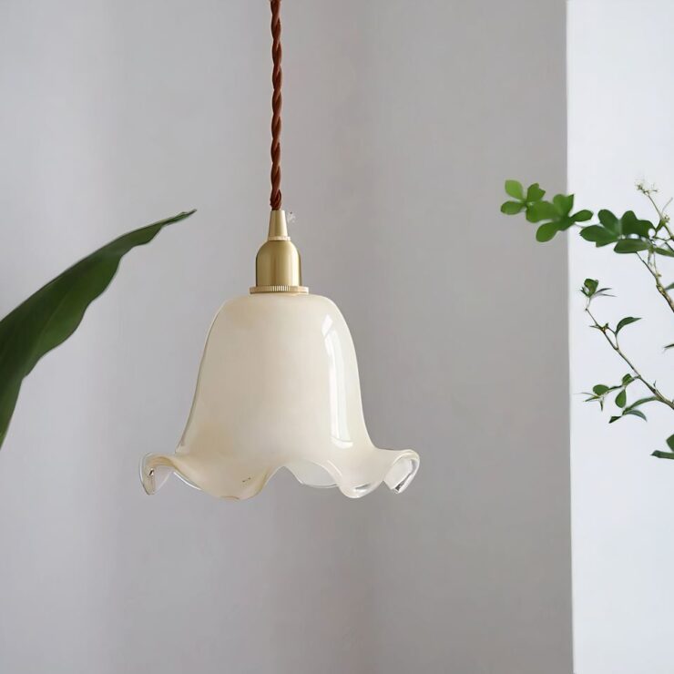 Un lustre opaline blanc en forme de fleur est suspendu avec un câble torsadé marron. Le design délicat rappelle une cloche florale avec des bords ondulés