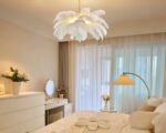 Un lustre chambre cocooning à plumes blanches est suspendu dans une chambre et offre une lumière douce et tamisée, créant une ambiance chaleureuse et apaisante.
