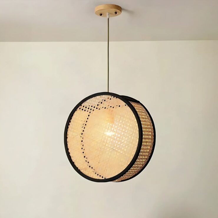 Lustre naturel circulaire en cannage suspendu fixé sur un plafond blanc. Le contour du cercle est noir. L'ampoule est allumée.