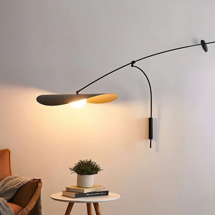 Lustre mural abat-jour chapeau original allumé et fixé sur un mur blanc et qui éclaire une petite tables basse sur laquelle est posée une petite plante verte.