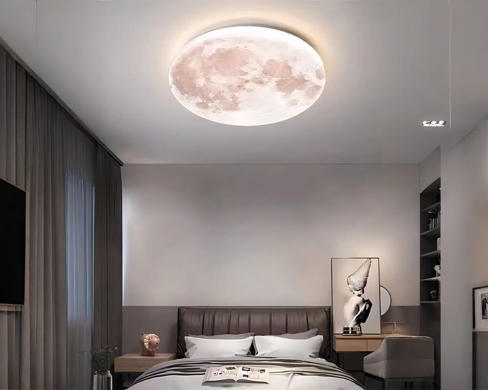 Lustre plafonnier lune chambre d'ado allumé et fixé au plafond d'une chambre aux tons gris et épurés. Il y a un cadre posé sur une table de chevet sur la gauche du lit.