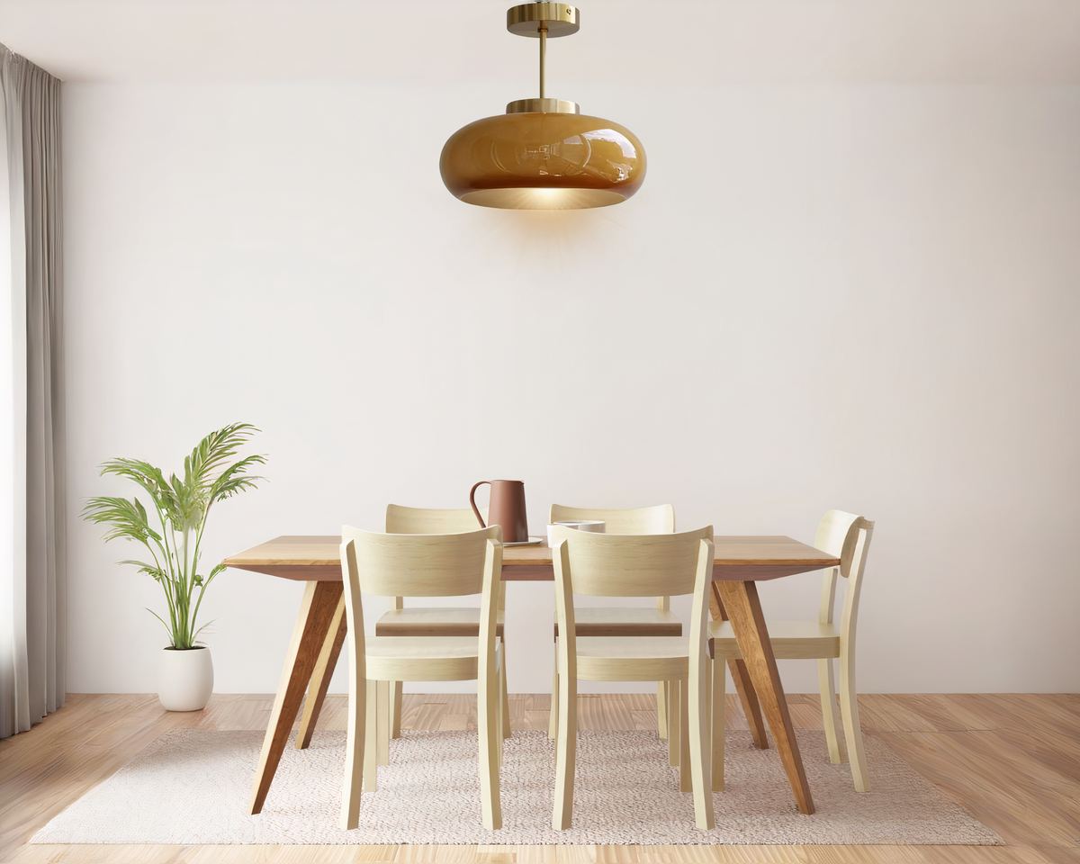 Lustre années 50 rond en verre ambré ou verre blanc suspendu au dessus d'une table de salle à manger au style très épuré et sur fond de mur blanc.