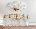 Cache plafond rosace décorative pour lustre, de couleur blanche, avec des motifs élégants en relief, ajoutant une touche sophistiquée au plafond et sublimant le lustre suspendu en dessous.