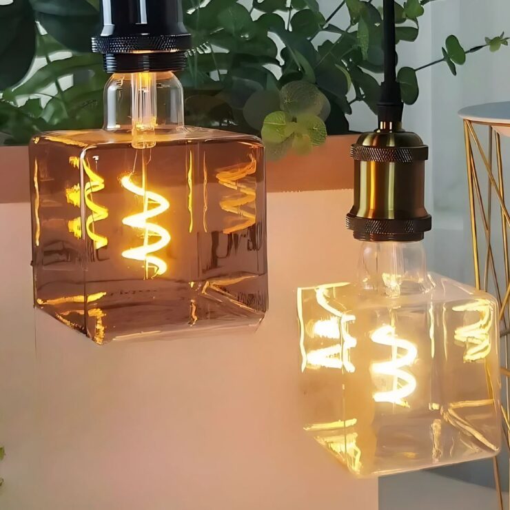 Deux lustres avec ampoule géante de forme carrée, dotée d'un filament en spirale, diffusant une lumière chaleureuse pour un effet décoratif moderne et original.