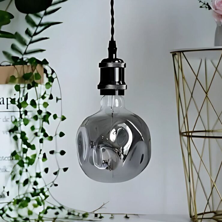 Lustre en forme d'ampoule géante avec un design déstructuré, offrant un look moderne et artistique, idéal pour une ambiance contemporaine.