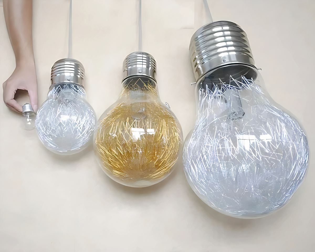 Lustre en forme d'ampoule géante disponible en versions dorées ou argentées et différentes tailles, avec des filaments décoratifs à l'intérieur, créant un effet lumineux étincelant pour une touche élégante et moderne.