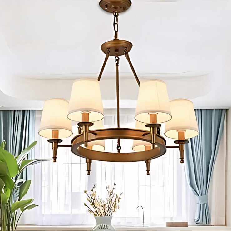 Lustre classique en fer forgé avec une structure circulaire dorée, ornée de cinq abat-jours en tissu blanc. Ce luminaire suspendu apporte une touche d'élégance intemporelle dans un salon.