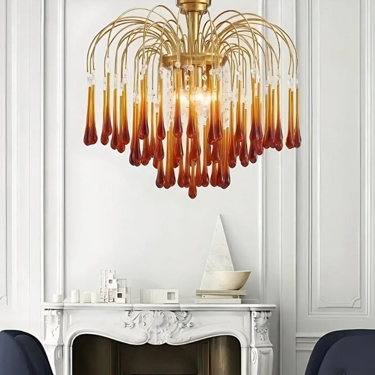 Lustre années 60 pluie de verre ambré allumé et suspendu dans une salle à manger et devant une ancienne cheminée blanche.