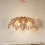Lustre Bali en forme de fleur en rotin tressé, devant un mur beige