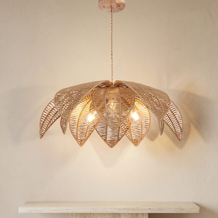 Lustre Bali en forme de fleur en rotin tressé, devant un mur beige
