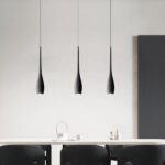 Un lustre suspendu forme goutte design contemporain avec trois suspensions noires fines, au-dessus d’une table dans une pièce moderne et épurée.