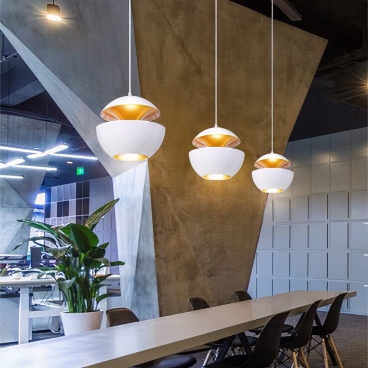 Trois suspensions en forme de boule, le lustre boule design noir intérieur doré, avec extérieur noir et lumière chaude dorée, suspendues sur un fond blanc minimaliste.